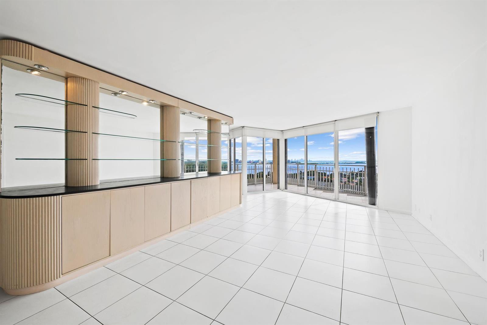 A bright living room features white tile floors, a built-in bar, and floor-to-ceiling windows — 1000 Quayside Terrace # 1606, Miami FL 33138, MIAMI, FL