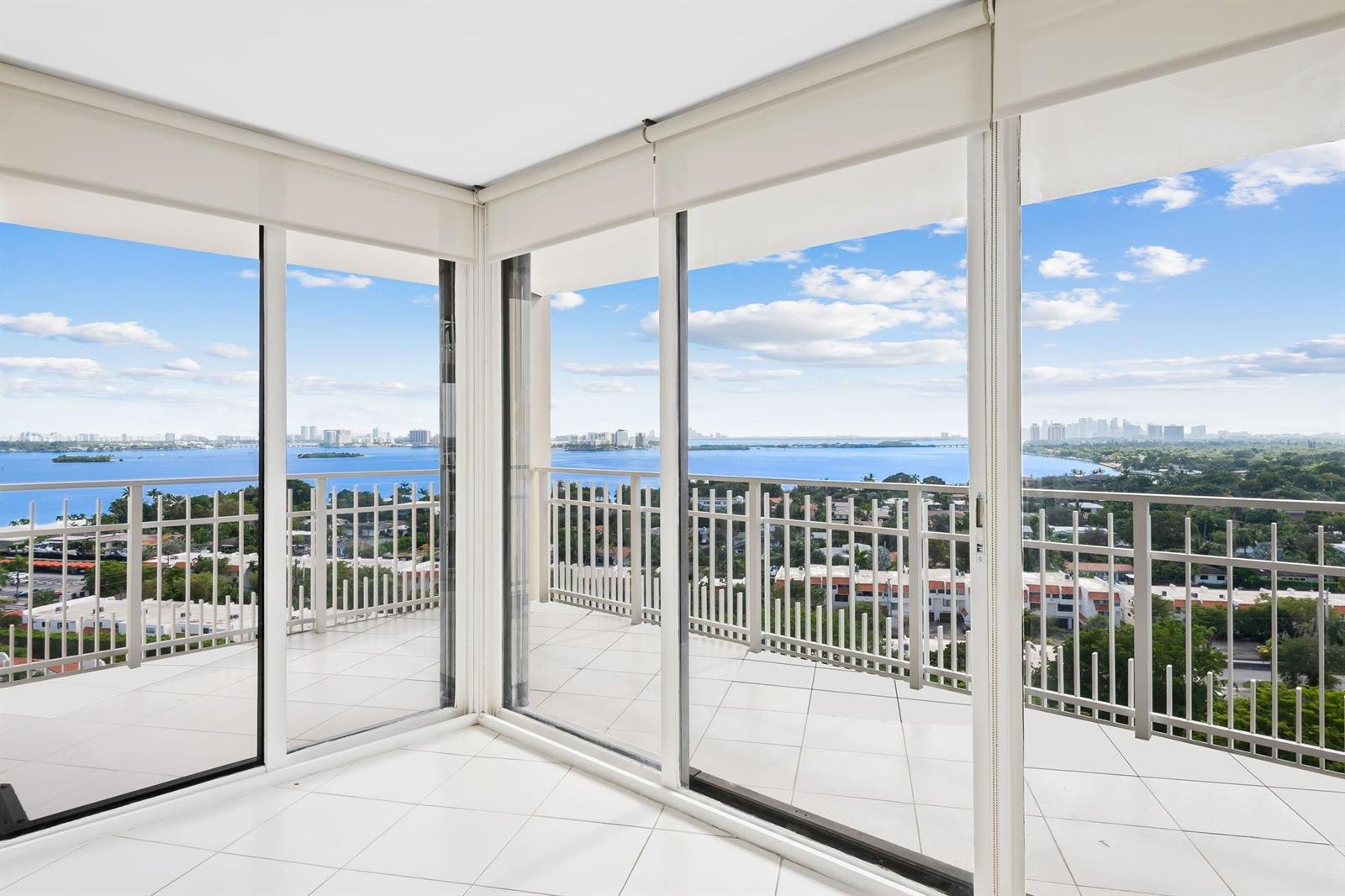 A bright, tiled room features floor-to-ceiling glass doors opening onto a balcony with water views — 1000 Quayside Terrace # 1606, Miami FL 33138, MIAMI, FL