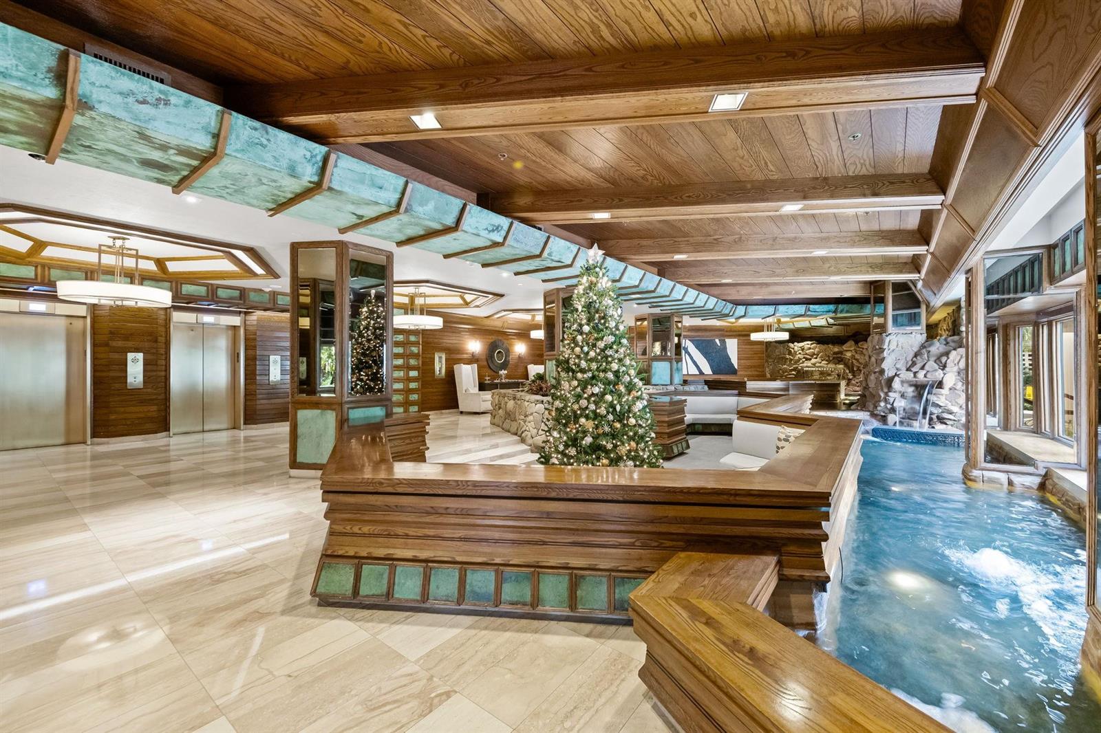 A lobby features wood-paneled ceilings, a Christmas tree, and an indoor water feature — 1000 Quayside Terrace # 1606, Miami FL 33138, MIAMI, FL