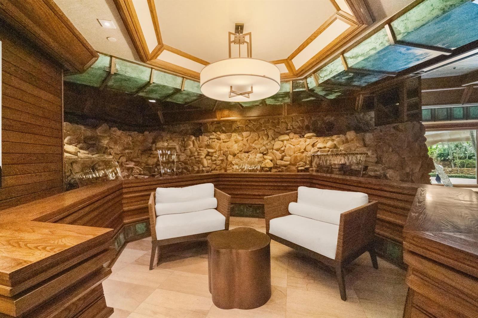 A seating area features two white chairs, a metal table, and a stone water wall — 1000 Quayside Terrace # 1606, Miami FL 33138, MIAMI, FL