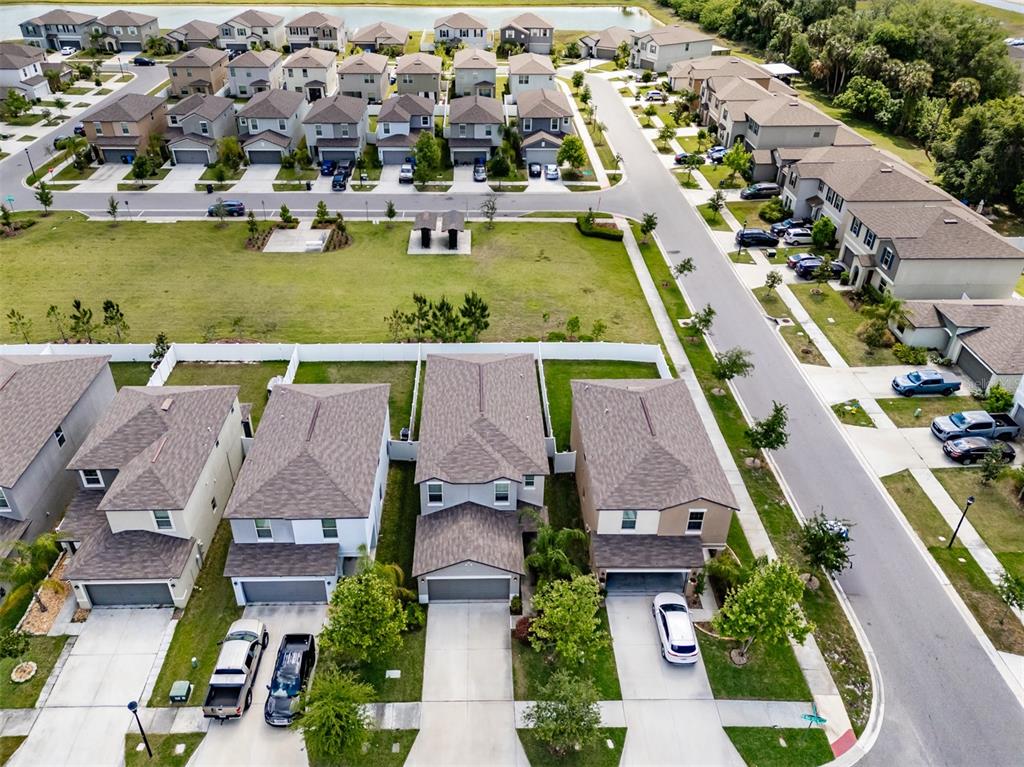 An aerial view shows a suburban neighborhood with detached houses, driveways, and a grassy park — 4712 RON EDDIE, TAMPA, FL