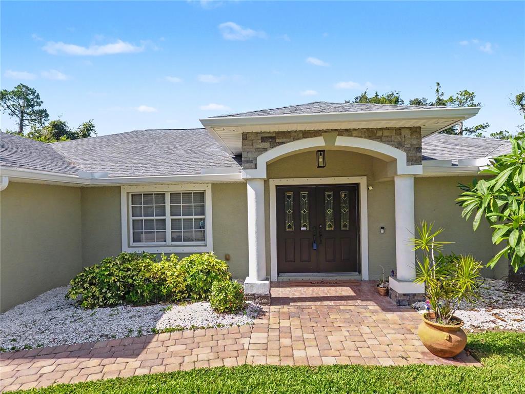 The exterior of a single-story house features a stone-accented entryway with double doors — 3283 SIKESTON AVENUE, NORTH PORT, FL
