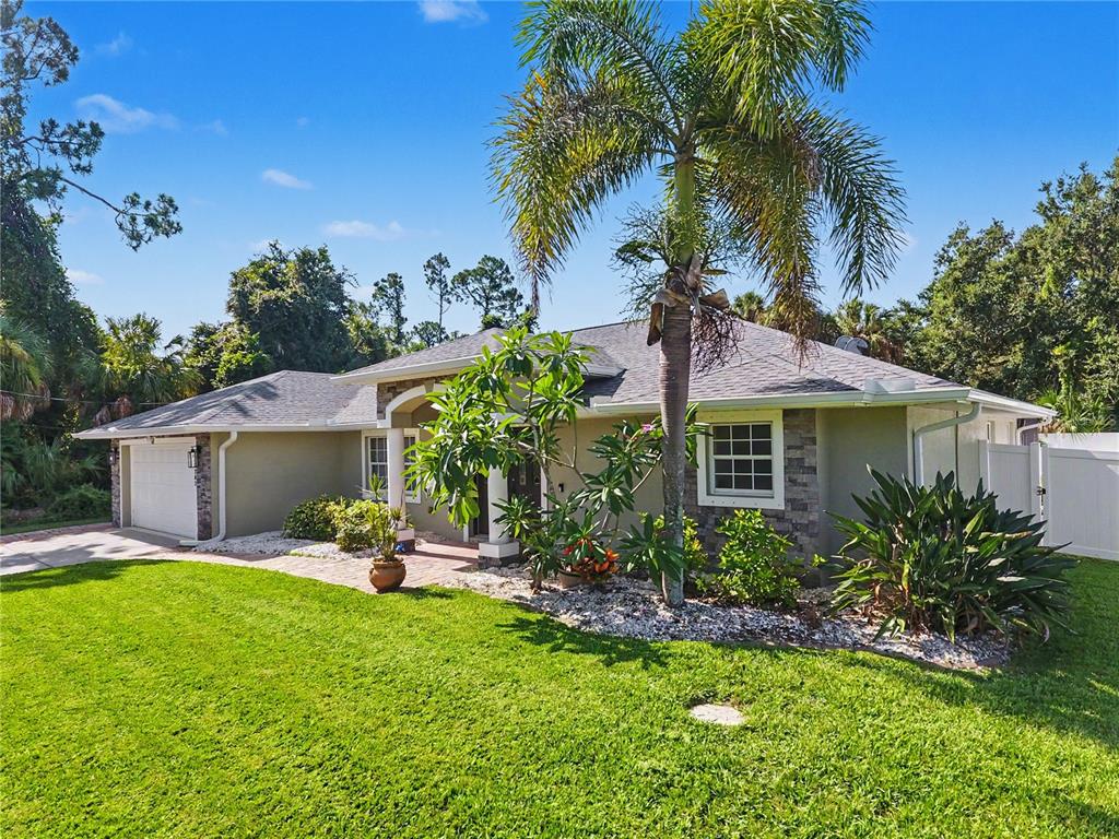 A single-story house with a tan exterior, stone accents, a palm tree, and a garage — 3283 SIKESTON AVENUE, NORTH PORT, FL