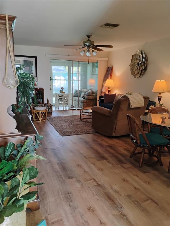 A living room with wood-look flooring, a ceiling fan, and a sliding door to a sunroom — 2465 NORTHSIDE DRIVE UNIT 1001, CLEARWATER, FL