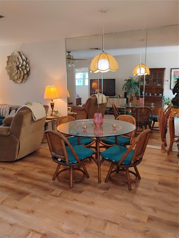 A dining area with a glass table, wicker chairs, and a large mirrored wall — 2465 NORTHSIDE DRIVE UNIT 1001, CLEARWATER, FL