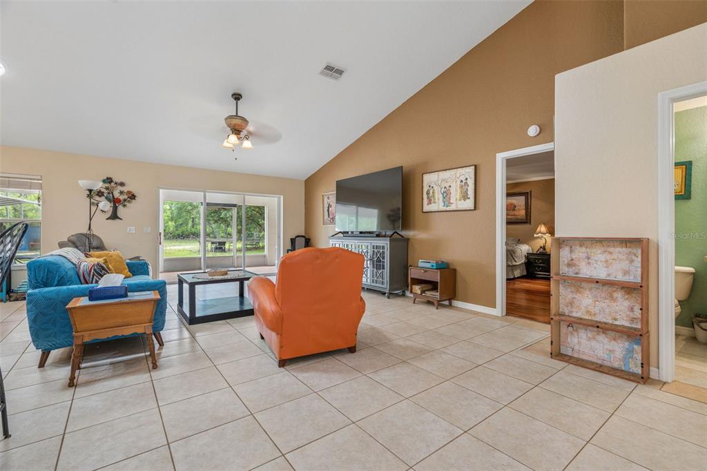 A living room with tile flooring, a vaulted ceiling, and an orange armchair — 4350 W HORSESHOE DRIVE, BEVERLY HILLS, FL