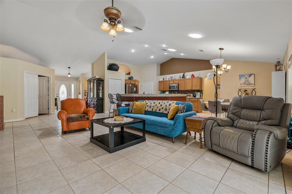 A living room features tile flooring, a blue sofa, an orange armchair, and a kitchen — 4350 W HORSESHOE DRIVE, BEVERLY HILLS, FL