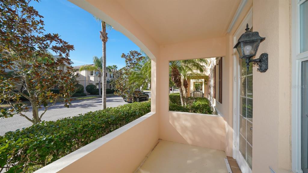 A covered outdoor patio features a light-colored floor, a wall-mounted lantern, and exterior views — 5373 DAVINI STREET, SARASOTA, FL