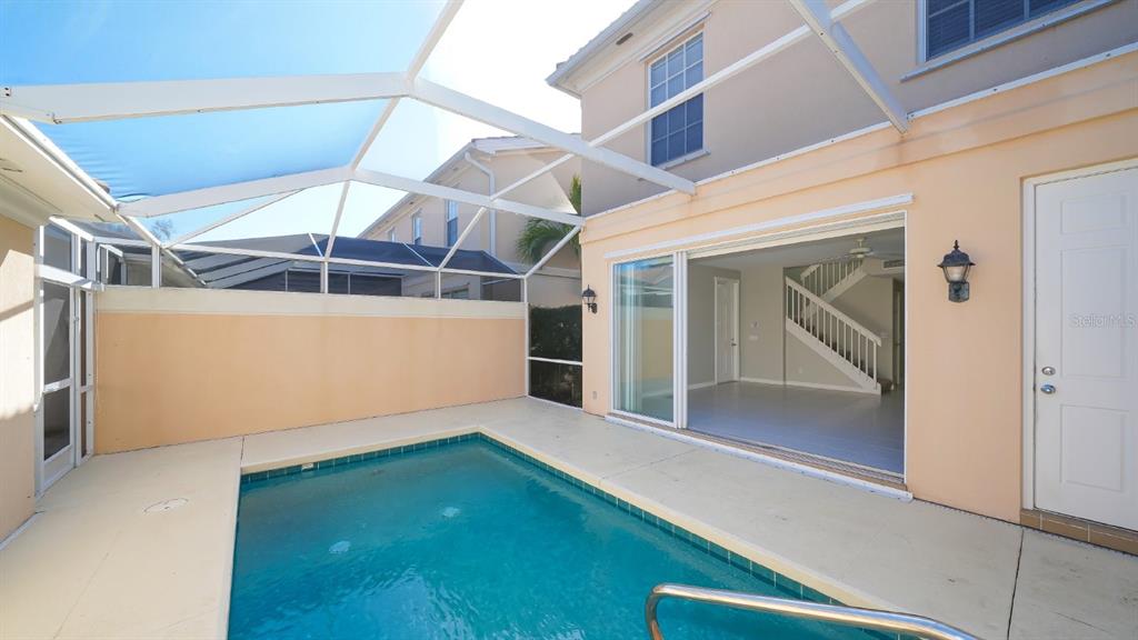 A small swimming pool sits on a patio enclosed by a screen cage next to a house — 5373 DAVINI STREET, SARASOTA, FL