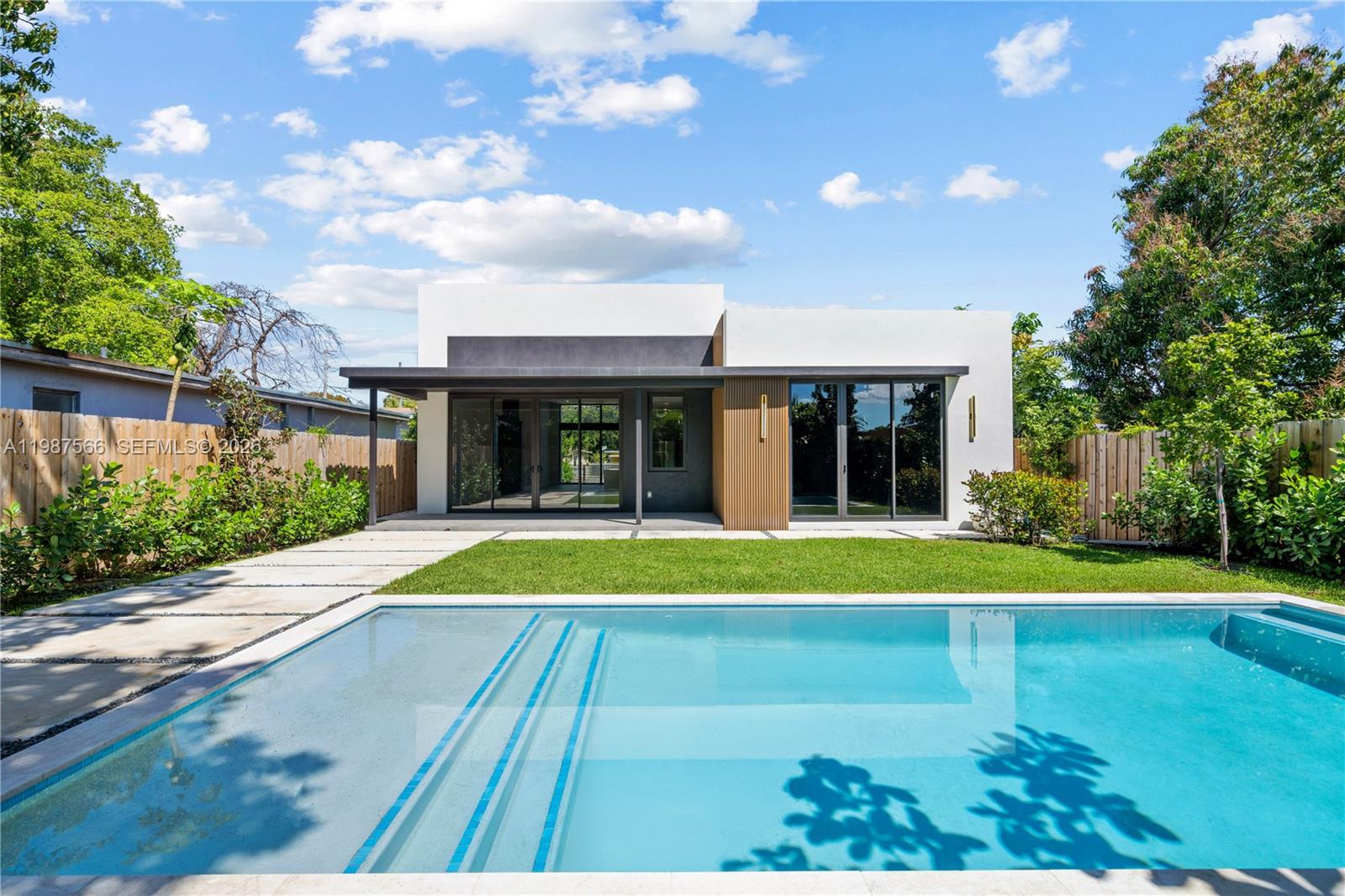 A modern house with a flat roof, wood-slat accents, and glass doors faces a pool — 412 NW 47th St, Miami FL 33127, MIAMI, FL