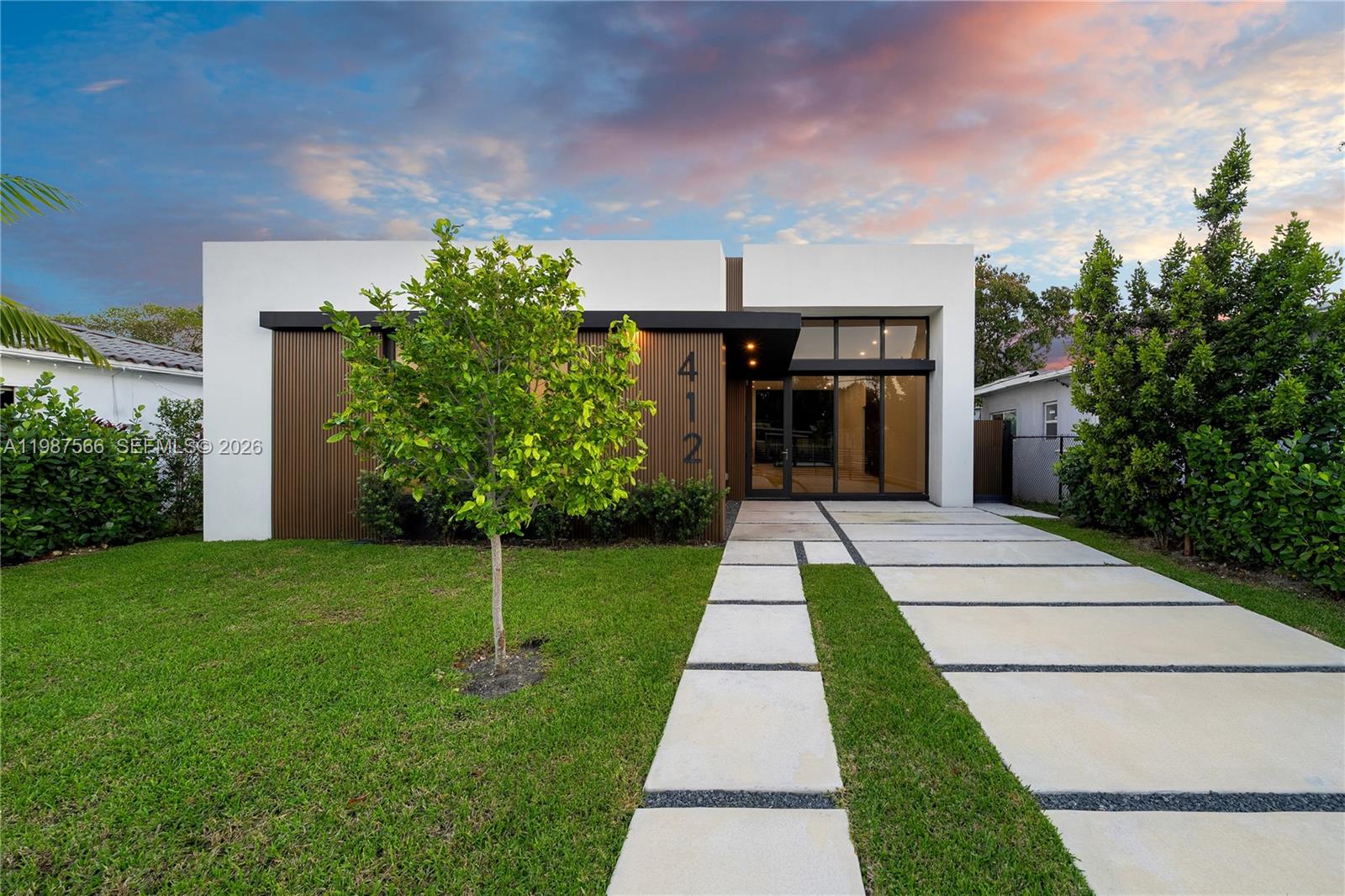 A modern single-story house features a white facade, vertical wood slats, and a concrete driveway — 412 NW 47th St, Miami FL 33127, MIAMI, FL