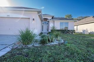 A single-story house with a light-colored exterior, a two-car garage, and a landscaped front yard — 2110 BUNKER VIEW COURT, KISSIMMEE, FL