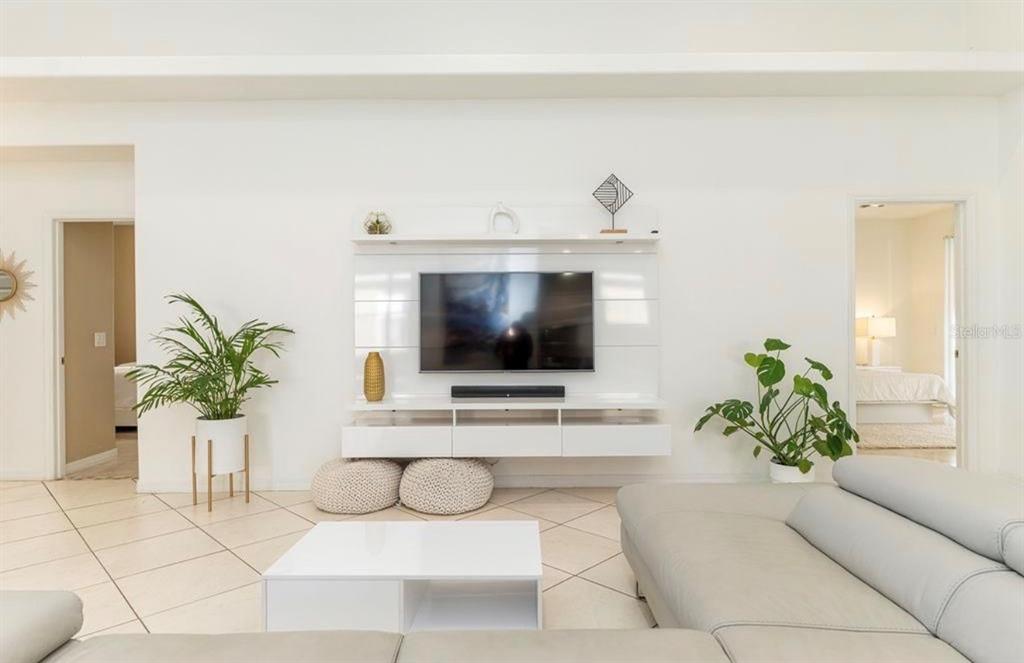 A living room features a white wall-mounted entertainment center, a large television, and tile flooring — 2110 BUNKER VIEW COURT, KISSIMMEE, FL