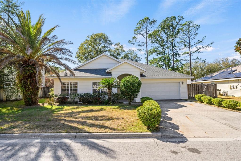 A single-story house with light siding, a two-car garage, and a palm tree in front — 4360 NW 36TH TERRACE, GAINESVILLE, FL