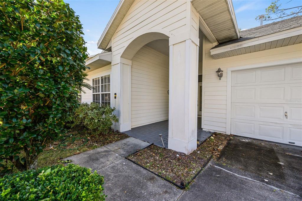 The exterior of a house features a covered entryway, a white garage door, and landscaping — 4360 NW 36TH TERRACE, GAINESVILLE, FL