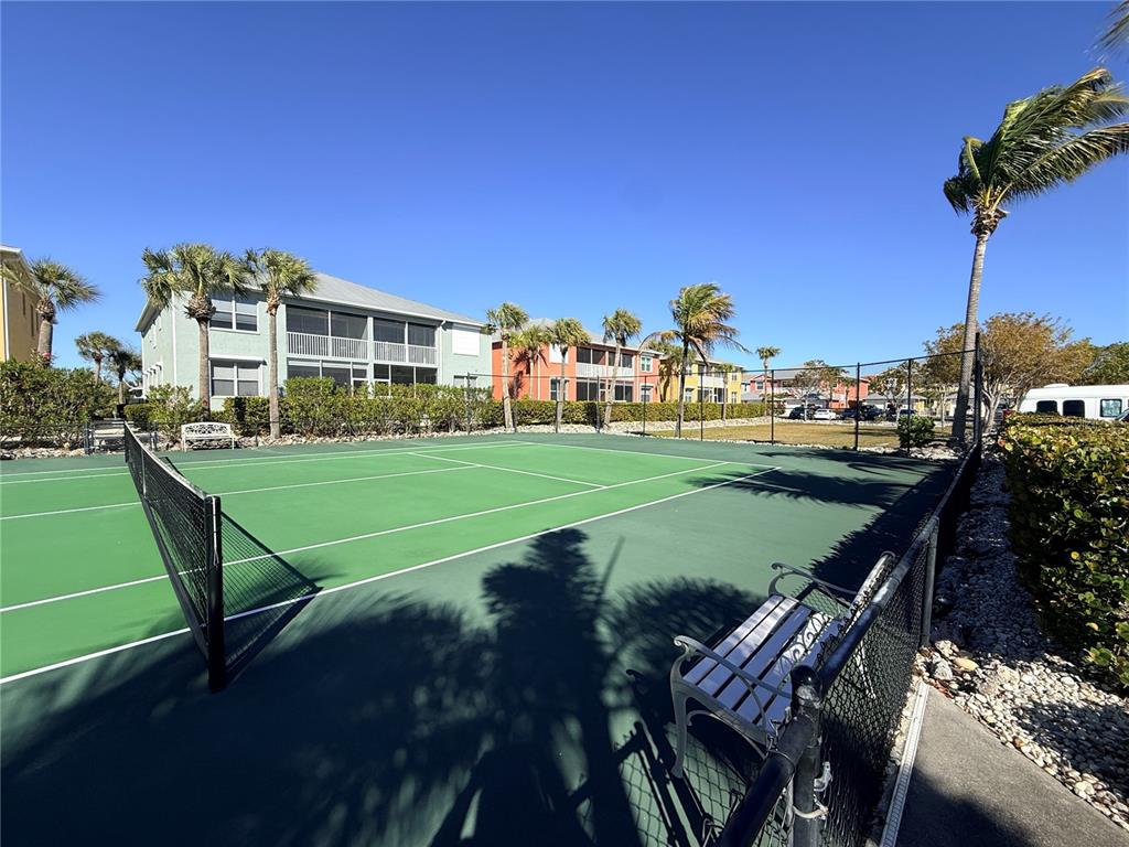 A green tennis court is surrounded by a chain-link fence, palm trees, and residential buildings — 2002 BAL HARBOR BOULEVARD UNIT 1512, PUNTA GORDA, FL