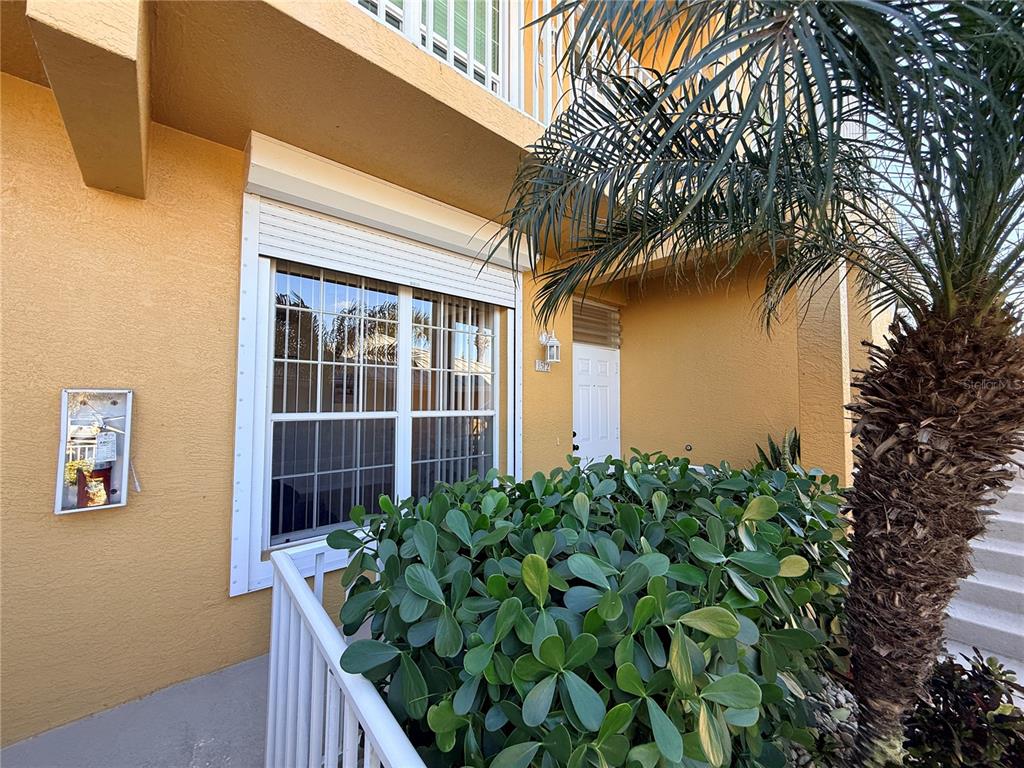 A yellow exterior wall features a window with a shutter and a white front door — 2002 BAL HARBOR BOULEVARD UNIT 1512, PUNTA GORDA, FL