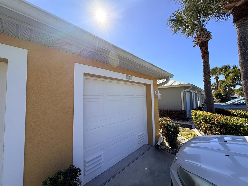 A tan house exterior features a white garage door, a white trim, and a palm tree — 2002 BAL HARBOR BOULEVARD UNIT 1512, PUNTA GORDA, FL
