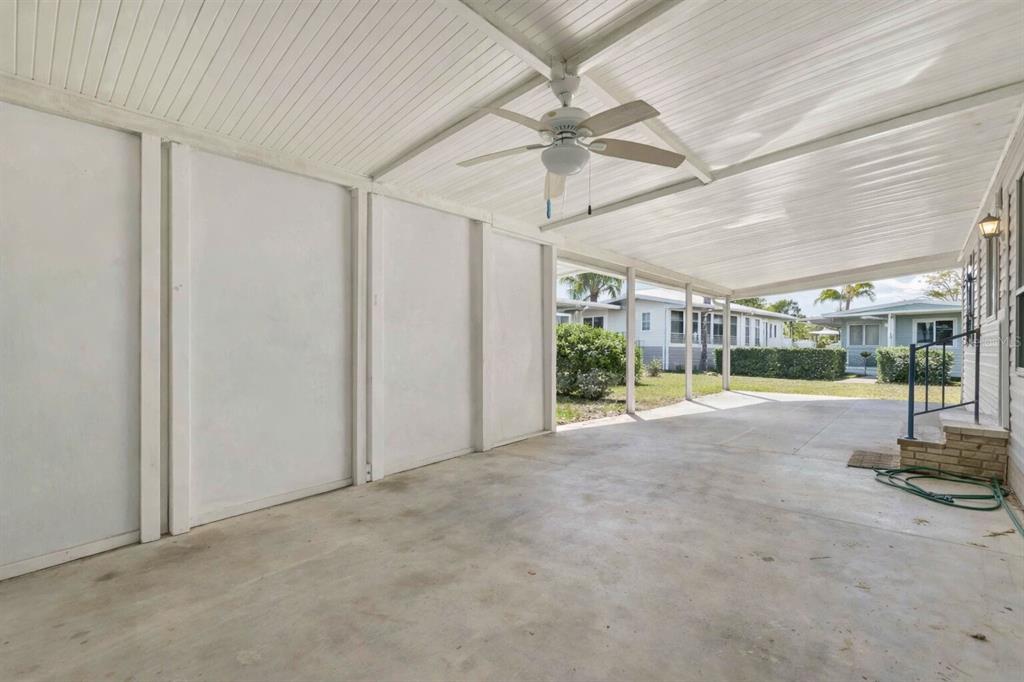 A covered concrete carport features a white ceiling with a ceiling fan and side walls — 10303 BURNT STORE ROAD UNIT 54, PUNTA GORDA, FL