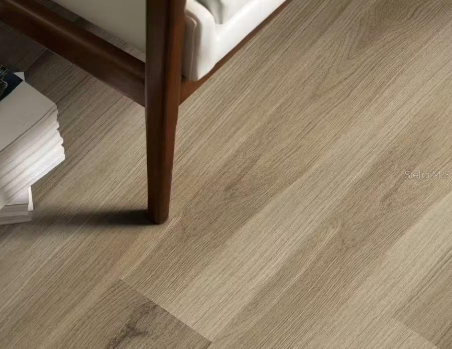 A close-up view of light wood-look flooring with a chair leg and stacked books — 4026 RUTILE ROAD, LAKELAND, FL