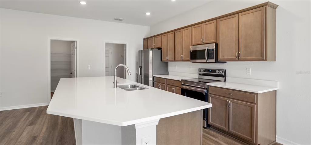 A kitchen features a large white island, wood cabinets, and stainless steel appliances — 4026 RUTILE ROAD, LAKELAND, FL