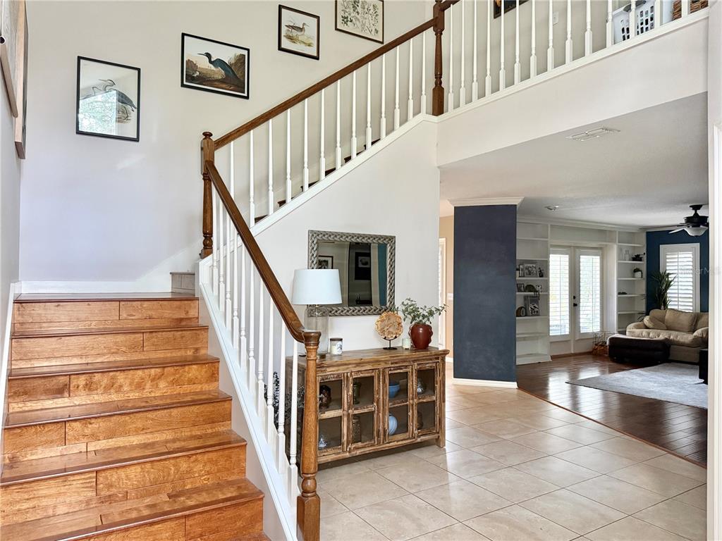 A foyer features a wooden staircase, tile flooring, and a console table with a lamp — 9306 ALANBROOKE ST, TEMPLE TERRACE, FL