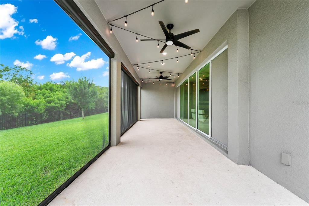 A covered patio features two ceiling fans, string lights, and a screened-in view of grass — 2314 NUTHATCH STREET, ST CLOUD, FL