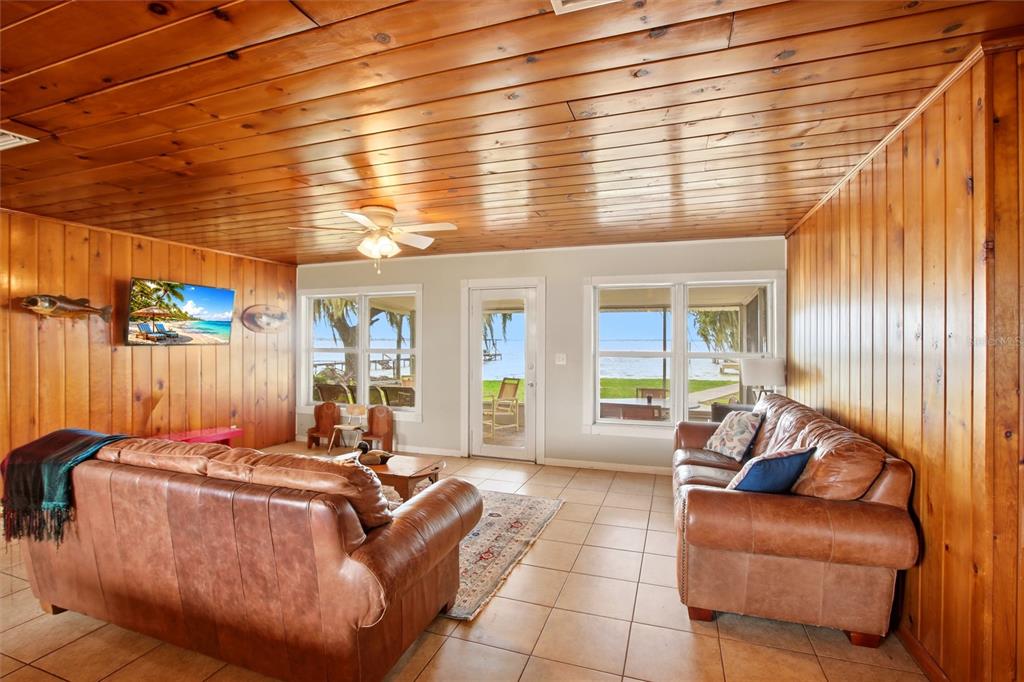 A living room features wood-paneled walls and ceilings, tile floors, and two leather sofas — 836 LAKE JUNE ROAD, LAKE PLACID, FL
