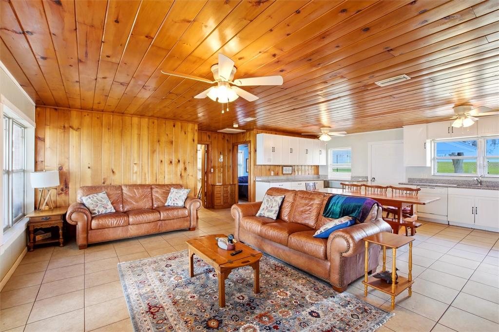 A living room with wood-paneled walls and ceiling, two leather sofas, and tile flooring — 836 LAKE JUNE ROAD, LAKE PLACID, FL