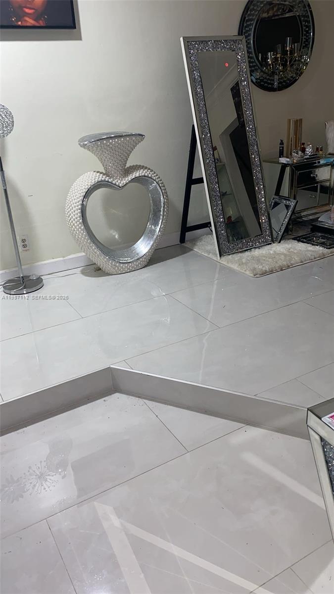 A modern room features white tile flooring, a heart-shaped decorative sculpture, and a tall, mirrored floor mirror — 4969 SW 7th St, Margate FL 33068, MARGATE, FL