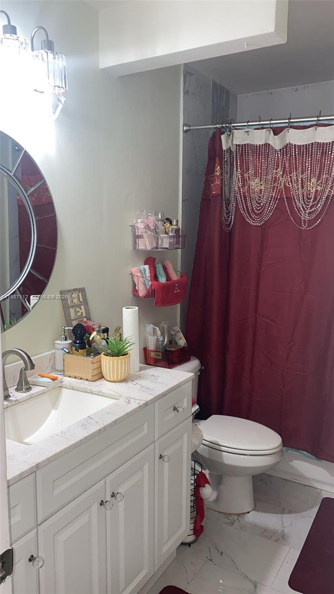 A bathroom features a white vanity, a round mirror, a toilet, and a red shower curtain — 4969 SW 7th St, Margate FL 33068, MARGATE, FL