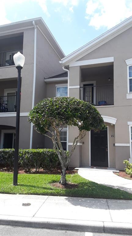A two-story apartment building exterior features a manicured tree in front of a dark door — 6512 SWISSCO DRIVE UNIT 1417, ORLANDO, FL