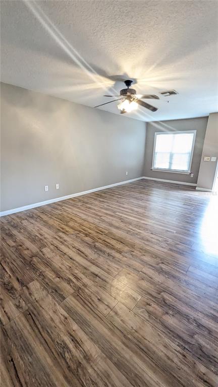 A spacious living room features wood-look flooring, a ceiling fan, and a large window — 6512 SWISSCO DRIVE UNIT 1417, ORLANDO, FL