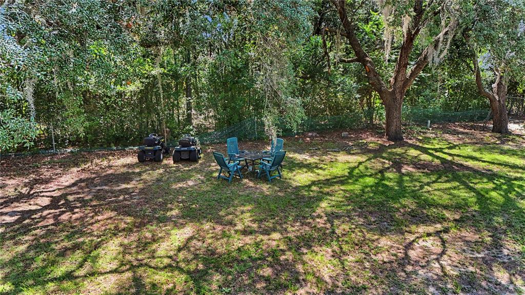 A backyard features a small table with four chairs and two riding lawn mowers — 20260 SW 80TH PLACE ROAD, DUNNELLON, FL