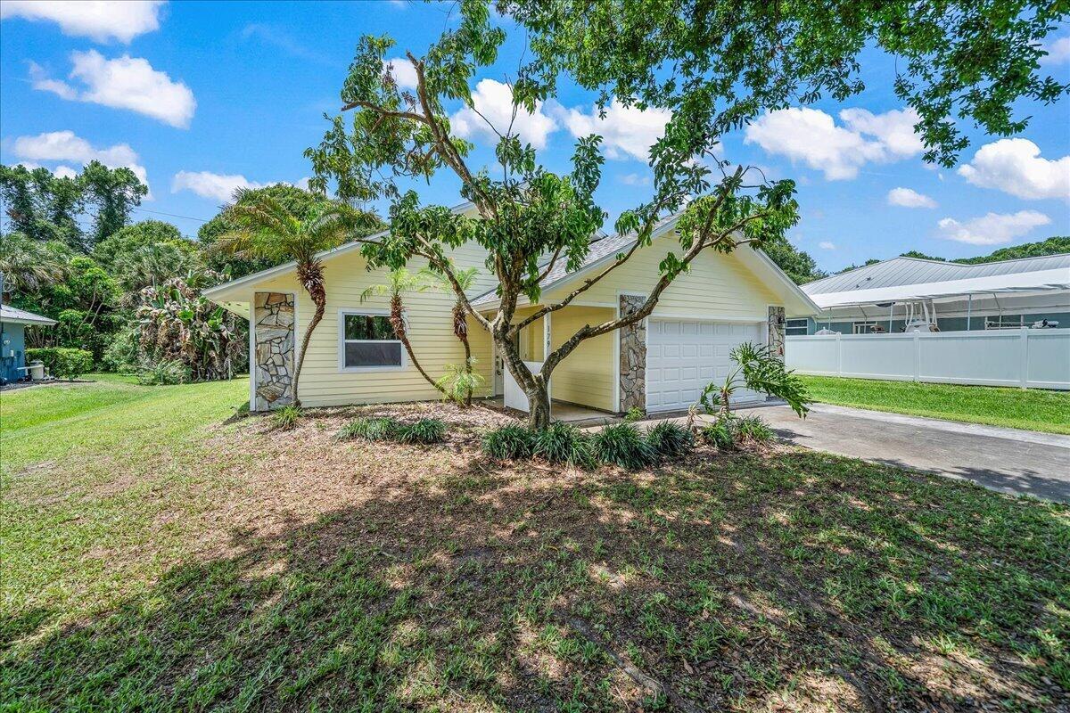 A yellow single-story house with a stone-accented garage and a large tree in the yard — 179 Filbert Street, Sebastian FL 32958, SEBASTIAN, FL