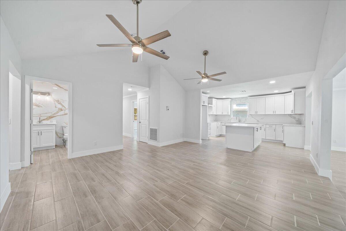An open-concept living area features light wood-look tile flooring, white cabinetry, and vaulted ceilings — 179 Filbert Street, Sebastian FL 32958, SEBASTIAN, FL