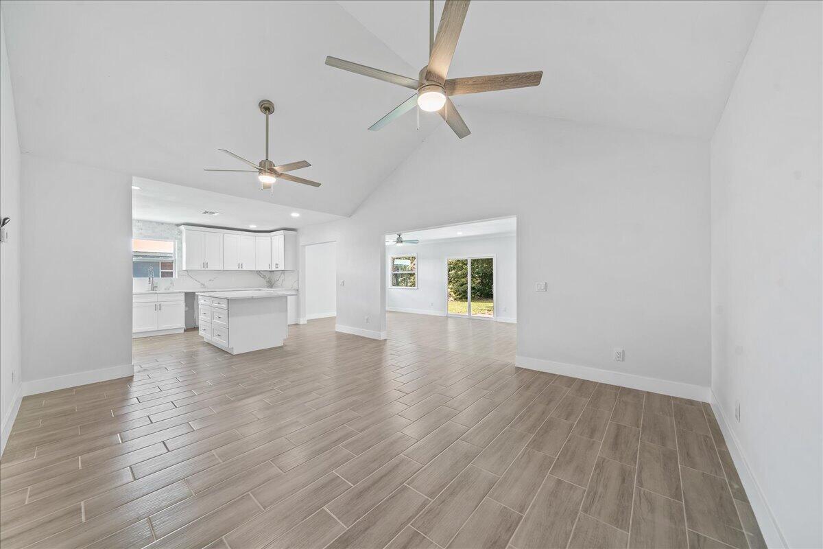 A bright, open-concept living area features vaulted ceilings, wood-look tile flooring, and a modern kitchen — 179 Filbert Street, Sebastian FL 32958, SEBASTIAN, FL