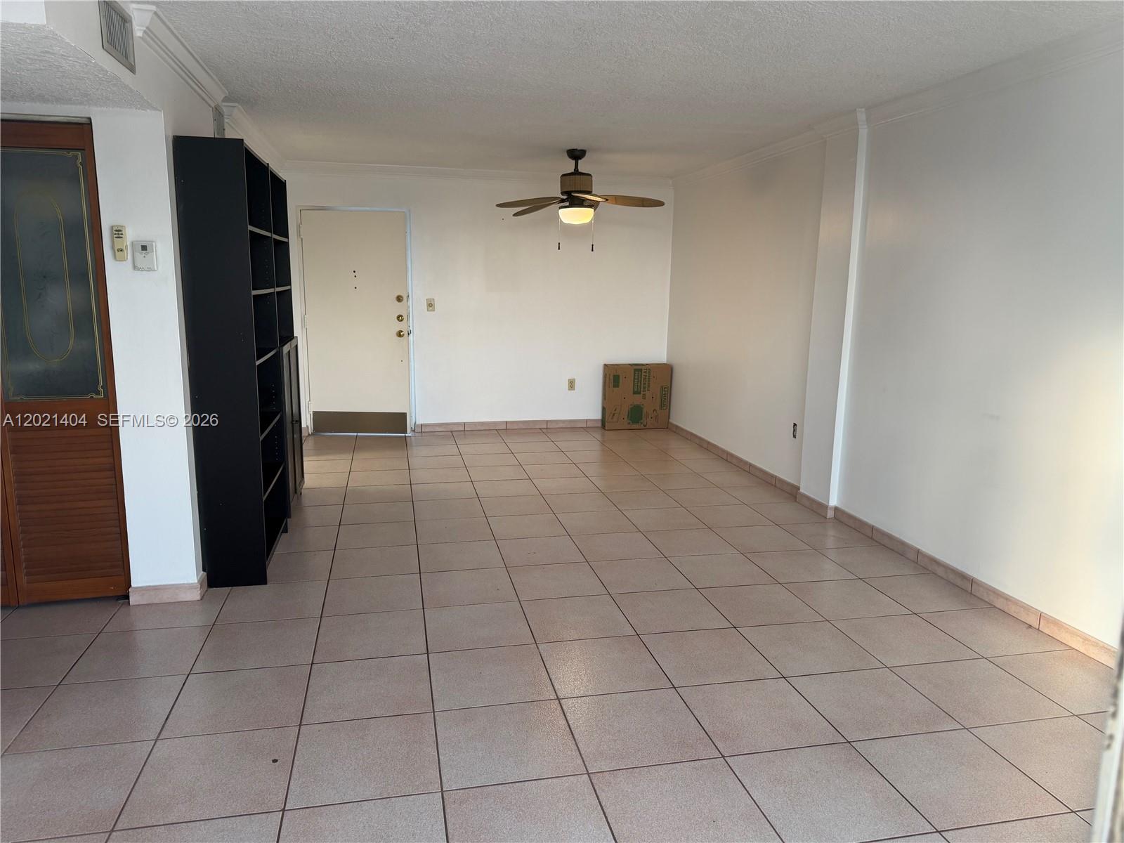 An empty room features light-colored floor tiles, white walls, a ceiling fan, and a bookshelf — 7300 Wayne Ave # 514, Miami Beach FL 33141, MIAMI BEACH, FL