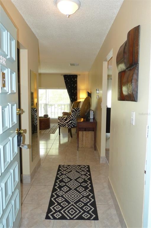 An entryway with tile flooring leads into a living room featuring a patterned area rug — 2700 BAYSHORE BOULEVARD UNIT 4312, DUNEDIN, FL