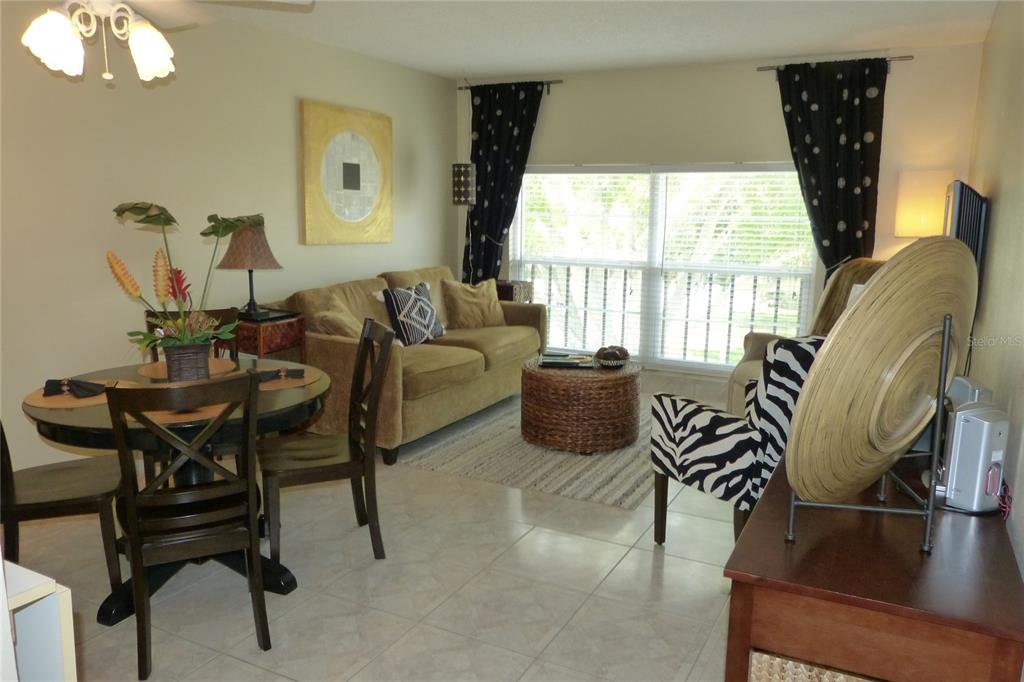 A living and dining area with tile floors, a tan sofa, and a zebra-print chair — 2700 BAYSHORE BOULEVARD UNIT 4312, DUNEDIN, FL