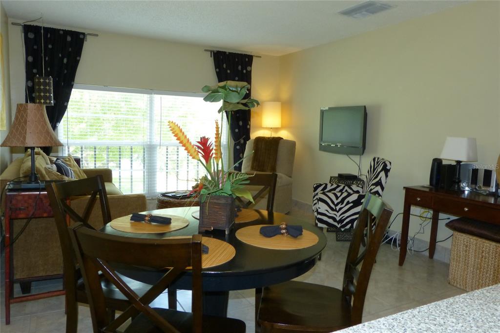 A dining area with a round table sits in front of a living room space — 2700 BAYSHORE BOULEVARD UNIT 4312, DUNEDIN, FL