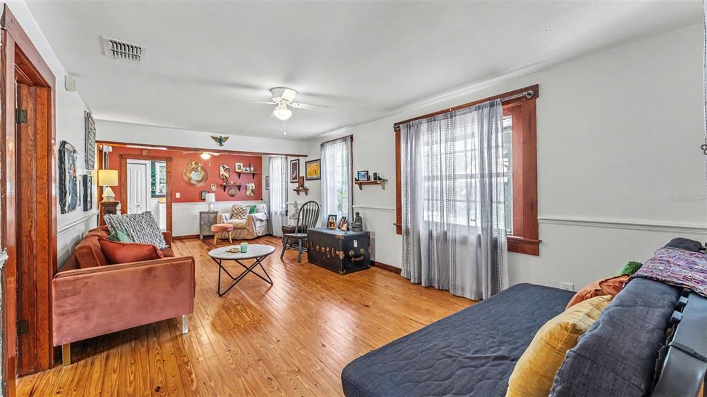 A living room features hardwood floors, a rust-colored sofa, a dark daybed, and wood trim — 1004 S EVERS STREET, PLANT CITY, FL