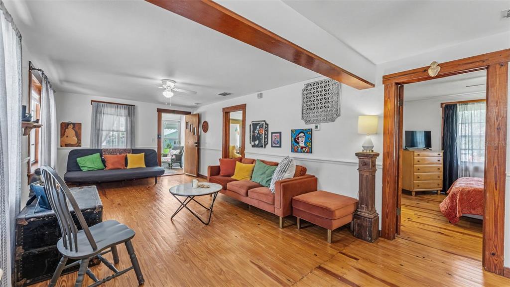 A bedroom features a bed with orange bedding, a wooden dresser, and hardwood floors — 1004 S EVERS STREET, PLANT CITY, FL