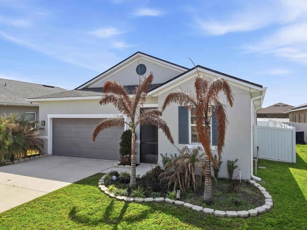 A single-story house with a gray garage, light-colored stucco walls, and two palm trees — 120 SUMMERSHORE DRIVE, AUBURNDALE, FL