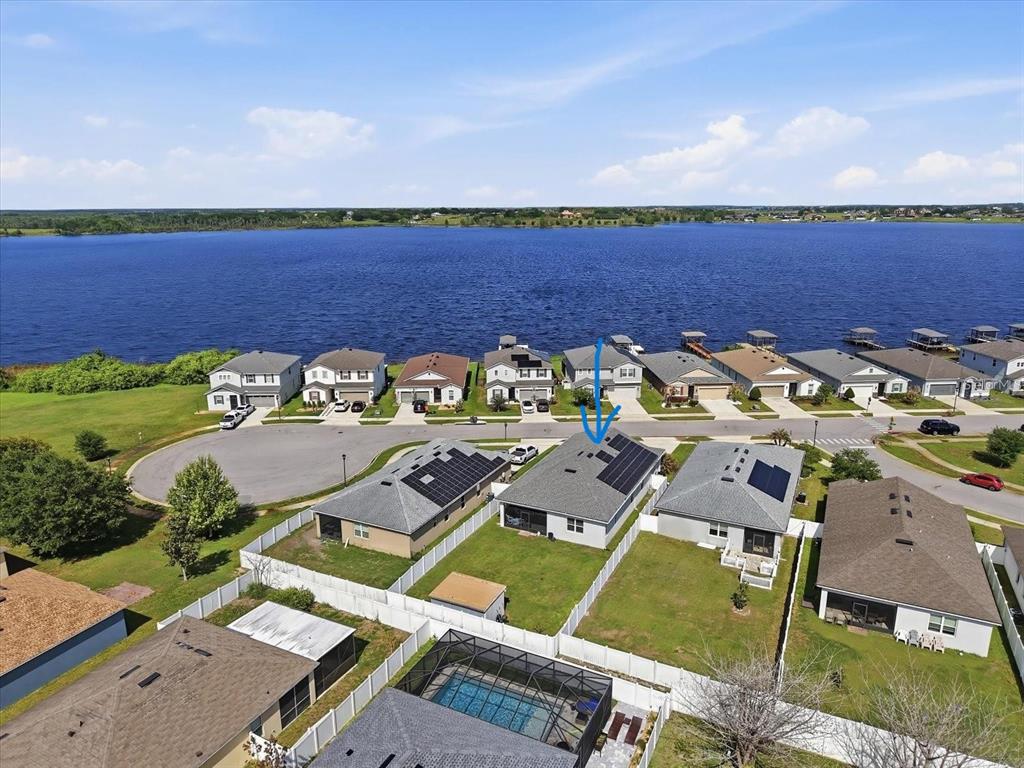 An aerial view shows a suburban neighborhood with houses featuring solar panels near a lake — 120 SUMMERSHORE DRIVE, AUBURNDALE, FL