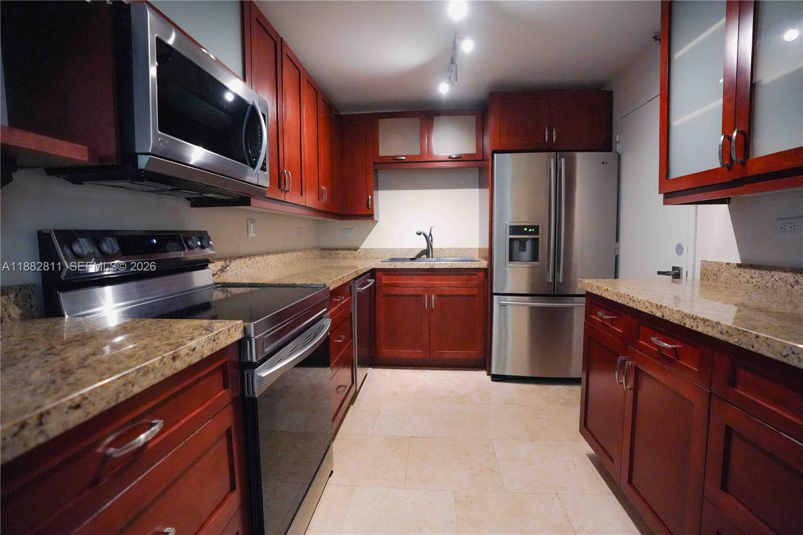 A kitchen features cherry wood cabinets, granite countertops, and stainless steel appliances — 6039 Collins Ave # 503, Miami Beach FL 33140, MIAMI BEACH, FL