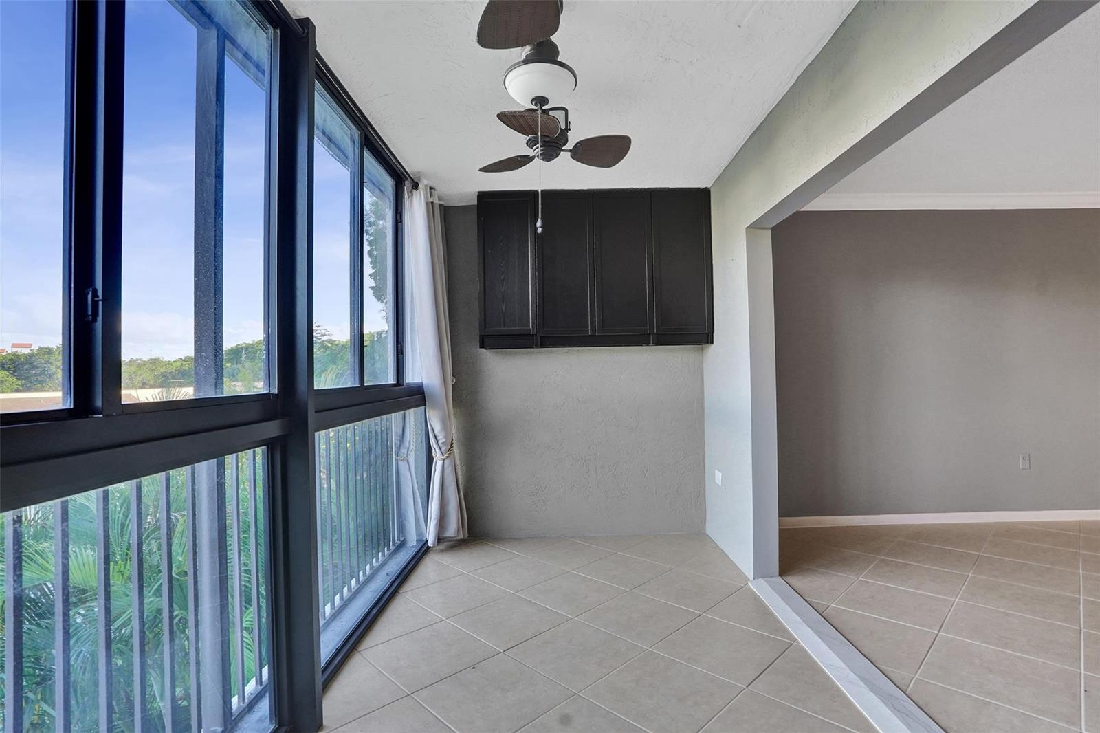 A sunroom with tile flooring, a ceiling fan, and dark cabinets mounted on a gray wall — 2334 S Cypress Bend Drive # 304, Pompano Beach FL 33069, POMPANO BEACH, FL