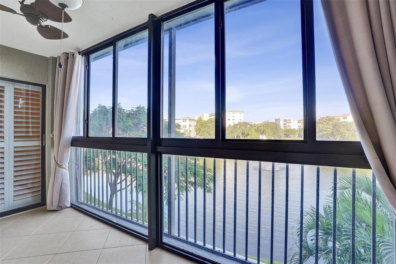 A sunroom with tile flooring, a ceiling fan, and large windows overlooking a lake — 2334 S Cypress Bend Drive # 304, Pompano Beach FL 33069, POMPANO BEACH, FL