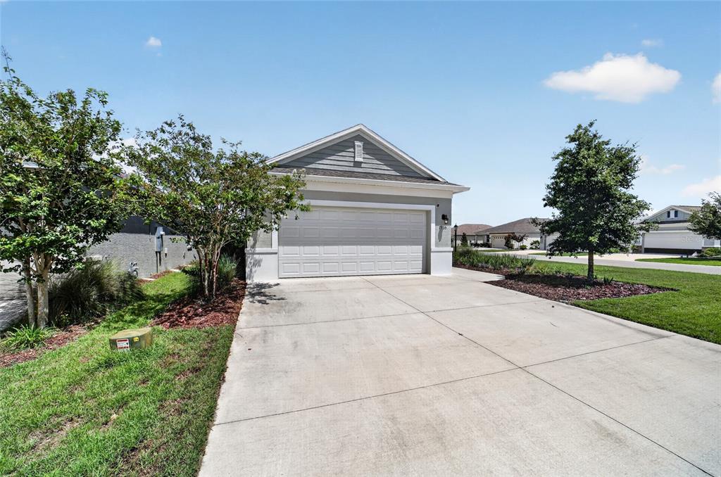 A single-story house with a beige exterior, a concrete driveway, and a large grassy yard — 7935 SW 89TH TERRACE, OCALA, FL