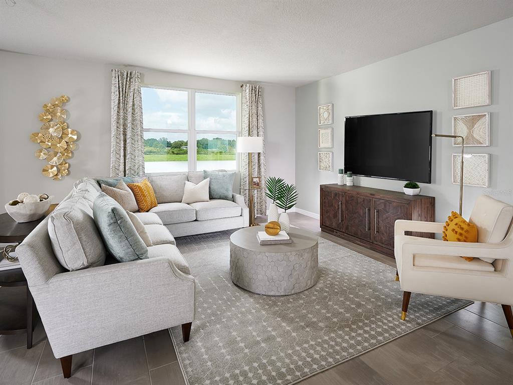 A living room features a sectional sofa, a round coffee table, and a wall-mounted television — 145 ARCHER DRIVE, LAKE ALFRED, FL